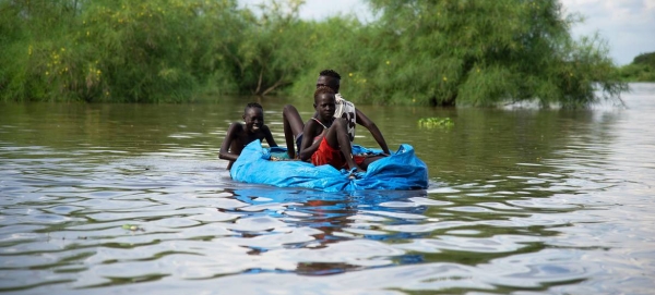 Children create their own boat using tarpaulin and plastic bottles during heavy flooding in South Sudan.
