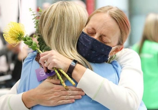 A woman is embraced by. a loved-one after arriving on a flight from Los Angeles at Sydney Airport as Australia open its borders for the first time in 19 months in Sydney, Monday.