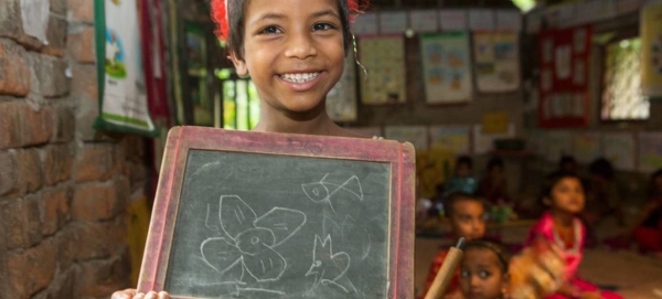 A child with disability happily holds the slate to display her drawing skills during a class at the UNICEF-supported BRAC pre-primary school in Soyghoria village, Bangladesh.
