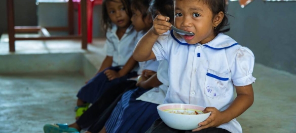 A young girl eats a meal in school before beginning class in Cambodia.