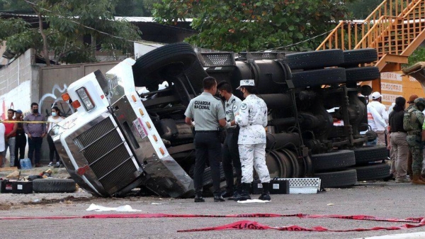 Pictures at the scene show the large truck and trailer overturned on a busy road.