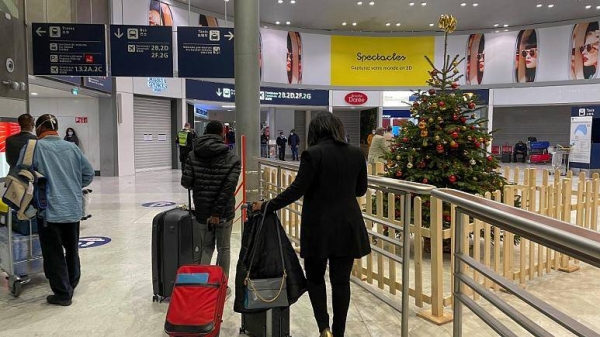 Arriving passengers walk by a Christmas tree at Paris Charles de Gaulle airport on Dec. 22, 2020.