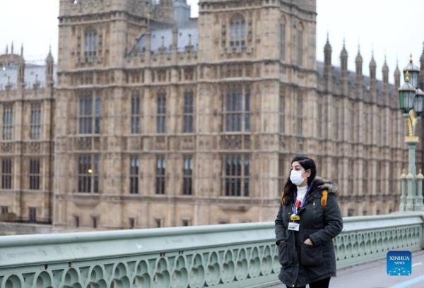 A woman wearing a face mask walks along Westminster Bridge in London. (Xinhua)   