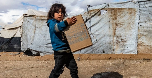 A child carries winter clothing kits, distributed by UNICEF, in Al-Hol camp in northeastern Syria.
