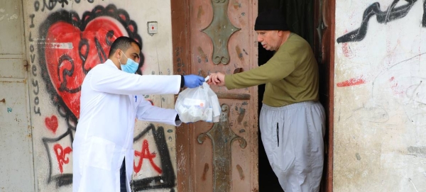 An UNRWA staff member provides medication to an elderly Palestinian man in the Gaza Strip.
