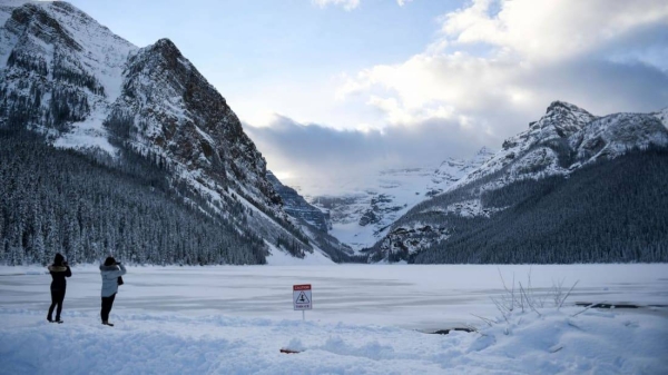 People take photographs in the snow at Lake Louise ahead of a winter storm in Banff National Park in Alberta, Canada.
