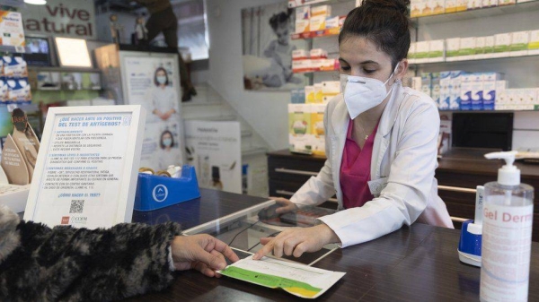 A pharmacist shows an antigen test to a person at a pharmacy in Madrid, Spain.
