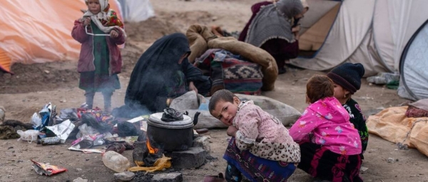 Children use the heat from a firewood stove to keep themselves warm in the hard Afghan winter.