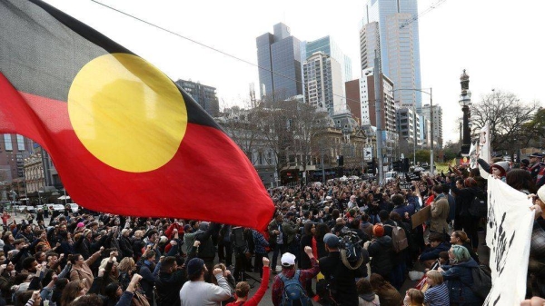 Protesters fly the Aboriginal flag over a march in Melbourne on Australia Day in 2019.