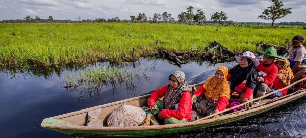 People are transported by boat on a river in Indonesia.