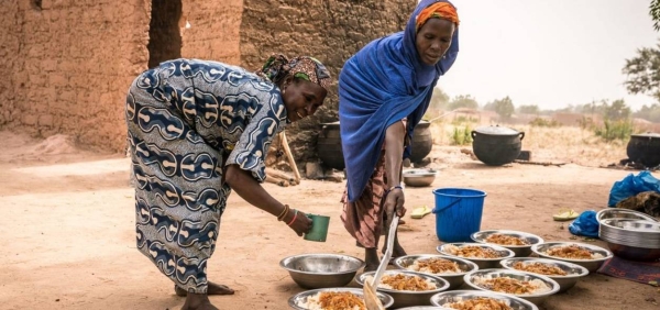 Mothers are dishing out the freshly prepared school lunch onto large plates in Niger.