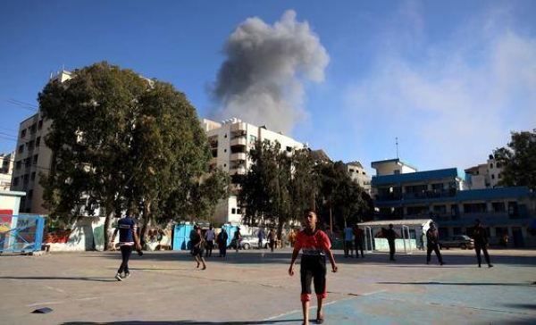 Children play football while an explosion occurs nearby, in the Gaza Strip, Palestine.