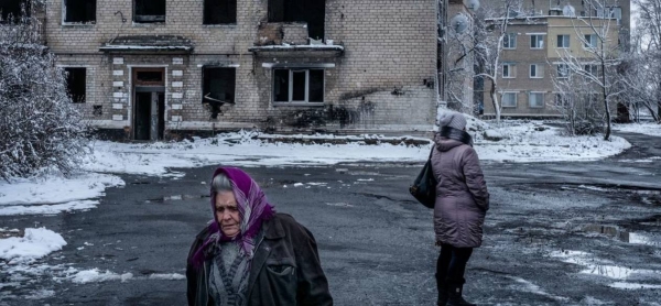 People walk past a residential building destroyed by shelling in Donetsk Oblast, Ukraine.