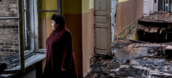 A woman stands in an abandoned school, damaged after a shell strike, in Krasnohorivka, Donetsk Oblast, Ukraine.