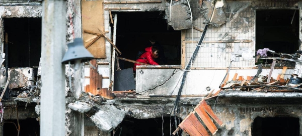 A woman works to clear debris in her apartment after the building was heavily damaged during ongoing military operations in Kyiv, Ukraine.