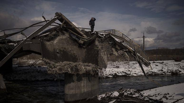 A man stands atop a destroyed bridge in Irpin, on the outskirts of Kyiv, Ukraine, Tuesday.
