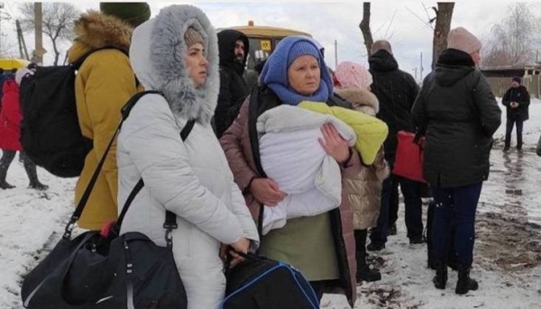 Women and children wait for evacuation buses to arrive.