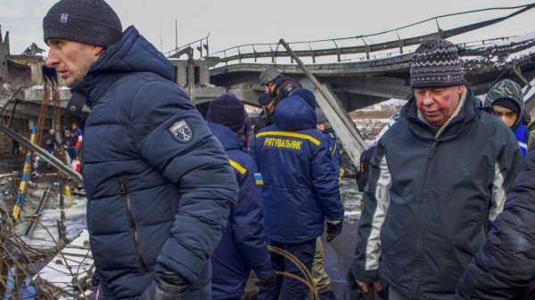 Residents of Irpin are seen evacuating from the frontline through a destroyed bridge under the assistance of the Ukraine police.