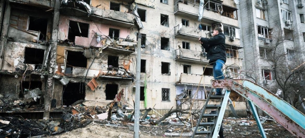 A man photographs an apartment building that was heavily damaged during escalating conflict, in Kyiv, Ukraine.
