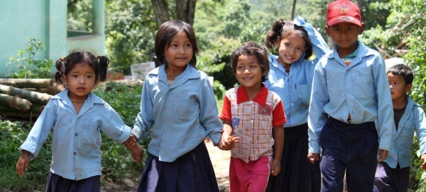 A group of school children walk hand in hand after school in rural Nepal.