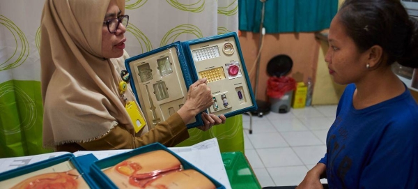 A female counselor shows a woman birth control options at health center in South Sulawesi, Indonesia.