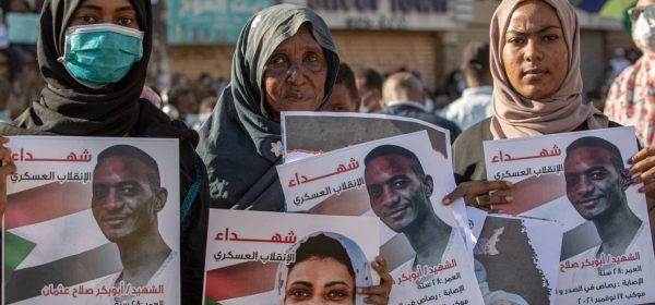 Three women in Khartoum hold pictures of their loved ones who died in protests, in Sudan.