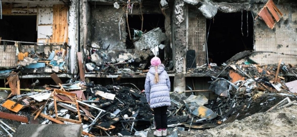 A woman looks at a crater left by an explosion in front of an apartment building that was heavily damaged during ongoing military operations in Kyiv.
