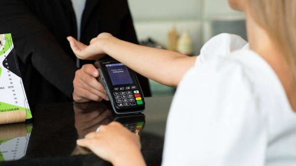 A woman paying for her meal in a café using a contactless payment chip implanted in her hand.