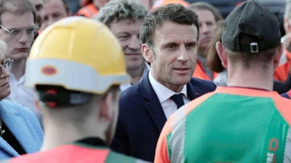 French President Emmanuel Macron is surrounded by a crowd of manual workers in northern France.