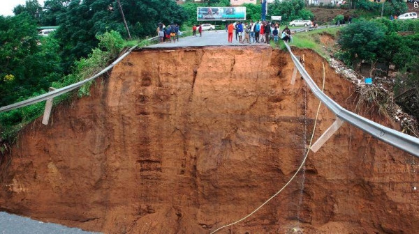 Stranded people stand in front of a bridge that was swept away in Ntuzuma, outside Durban in South Africa on Tuesday, following heavy rains.