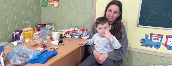 A mother who fled Bucha with her family sits with her son at their current refuge in Zakarpattia, Ukraine. — courtesy IOM/Jana Wyzinska