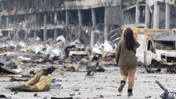 A young woman with a mobile phone takes pictures of a destroyed Retroville shopping center in Kyiv following a Russian shelling attack.