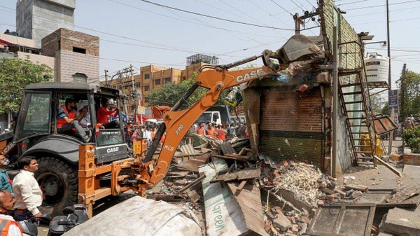 A bulldozer demolishes a structure during a joint anti-encroachment drive conducted by North Delhi Municipal Corporation at Jahangirpur.
