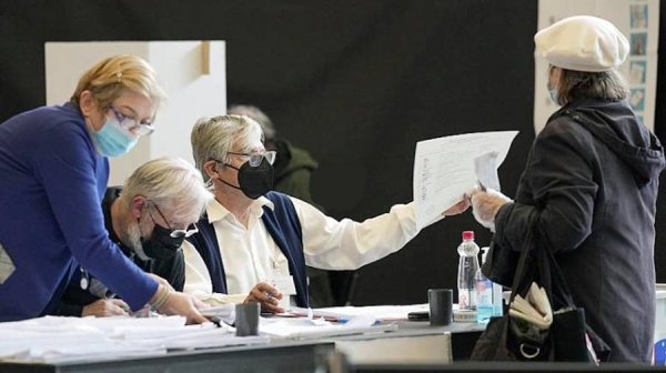 A voter is passed a ballot at a polling station for early voting in Ljubljana on Thursday.