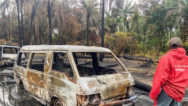 A man near burned-out vehicles after an explosion at an illegal oil refinery in the Niger Delta, Nigeria.