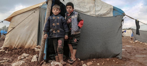 Children, whose families were displaced due to the war in Syria, stand outside their shelter, in the north of the country.