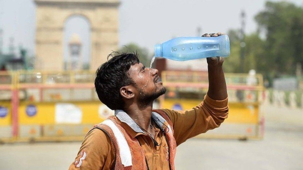 A worker pours water on his face amid the scorching heat near India Gate in Delhi.