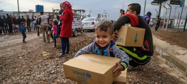 A three-year-old boy sits on a box of winter clothing that his family has received from a distribution center at Kawergosk Syrian Refugee Camp in Erbil Governorate in the Kurdistan region of Iraq.