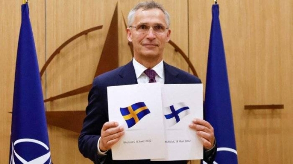 NATO Secretary-General Jens Stoltenberg displays documents as Sweden and Finland applied for membership in Brussels, Belgium, Wednesday.