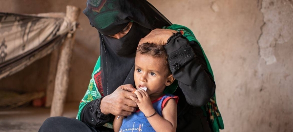 A woman sits with her son at the family's makeshift home in Lahj, Yemen.