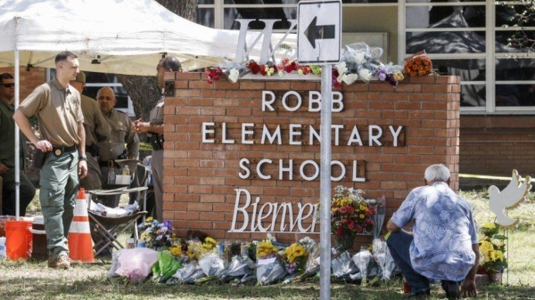 Officers stand near a memorial of flowers at the scene of the mass shooting at the Robb Elementary School in Uvalde, Texas.