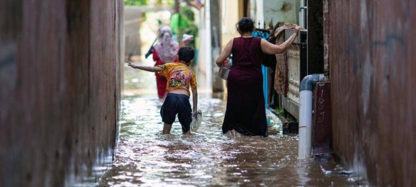 A boy and his mother walk through a flooded area in East Jakarta, Indonesia. in February 2021. — courtesy UNICEF/Arimacs Wilander