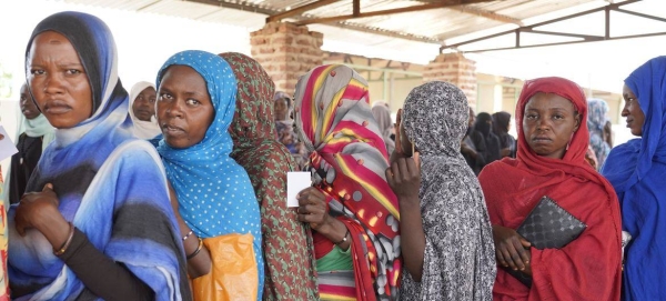 Women wait in line to receive cash distributions in Sudan.