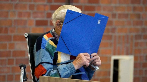 Josef S. covers his face as he sits at the court room in Brandenburg, Germany, Thursday, Oct. 7, 2021.