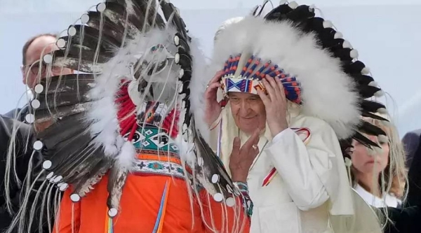Pope Francis puts on an indigenous headdress during a meeting with indigenous communities, in Maskwacis, near Edmonton, Canada, Monday.