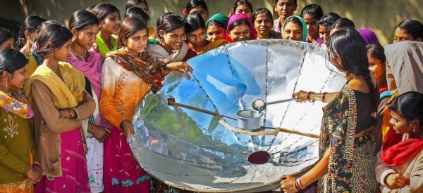 In India, a woman demonstrates how to use a solar dish for cooking.