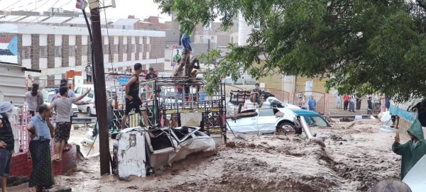People stand on vehicles that were wrecked by the floods in Yemen.