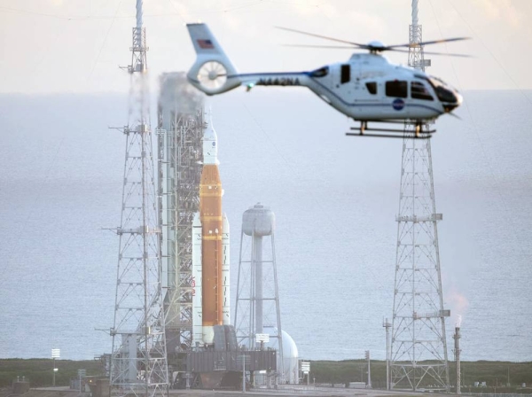 
A NASA helicopter flies past the agency’s Space Launch System (SLS) rocket with the Orion spacecraft aboard atop the mobile launcher at Launch Pad 39B at NASA’s Kennedy Space Center in Florida, Monday, Aug. 29, 2022. NASA’s Artemis I flight test is the first integrated test of the agency’s deep space exploration systems: the Orion spacecraft, SLS rocket, and supporting ground systems. — courtesy NASA