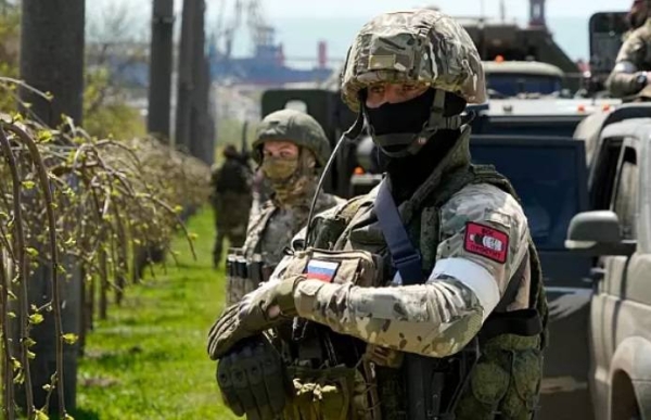 Russian servicemen stand near their military vehicles in Berdiansk with the Azov Sea in the background,