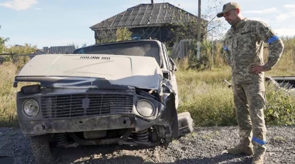 A Ukrainian soldier beside a Russian vehicle, with the Z marking, in the Kharkiv region on Friday